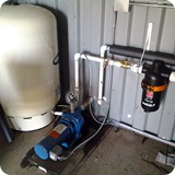 Indoor view of 1 horsepower booster pump system with pressure tank and filter.